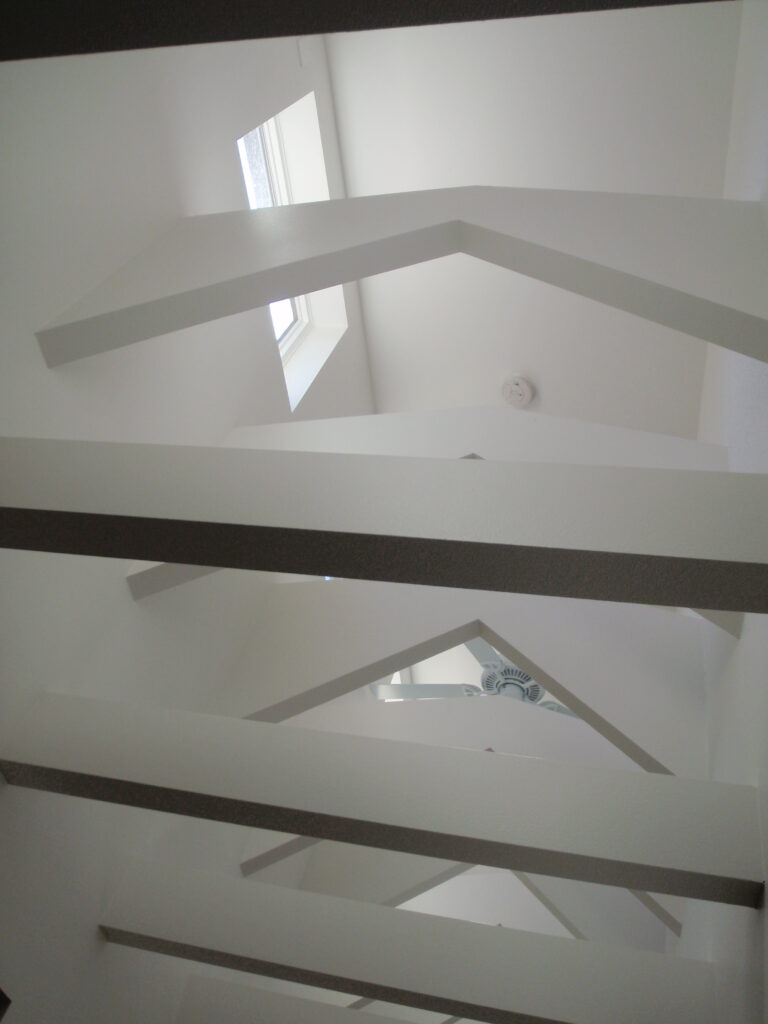 Modern interior architecture featuring white structural ceiling beams, skylights, and natural daylight design