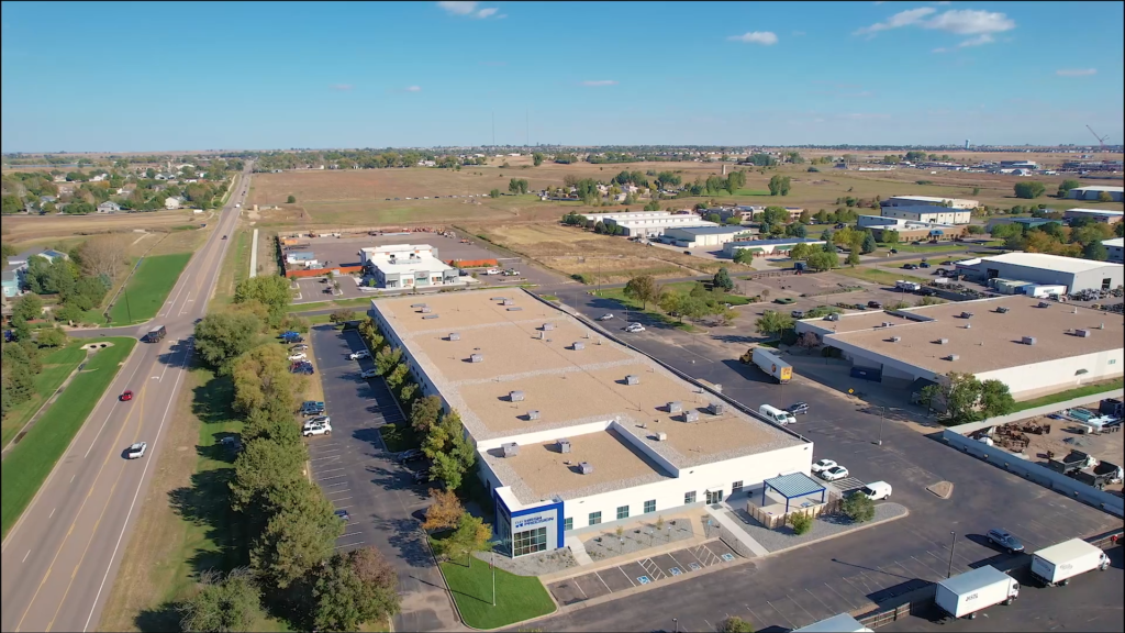 Aerial view of a large industrial manufacturing facility with surrounding commercial buildings and roads