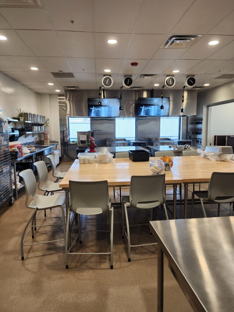 Modern culinary training kitchen with cooking stations, work tables, and professional equipment
