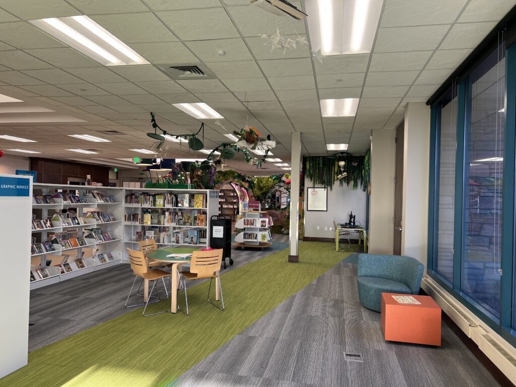 Creative library interior with bookshelves, reading tables, colorful carpet areas, and modern seating spaces
