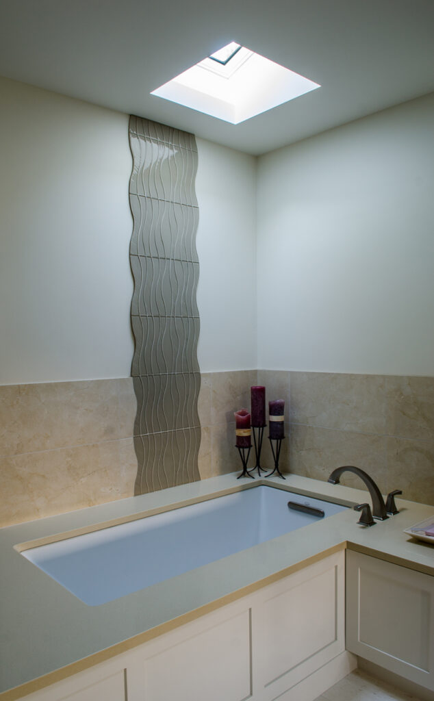 Modern bathroom interior with corner soaking tub, skylight, decorative tile wall, and contemporary fixtures