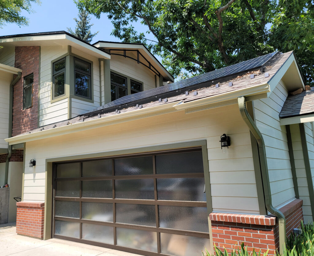 Modern house exterior with solar panels on roof, brick accents, large garage door, and contemporary design