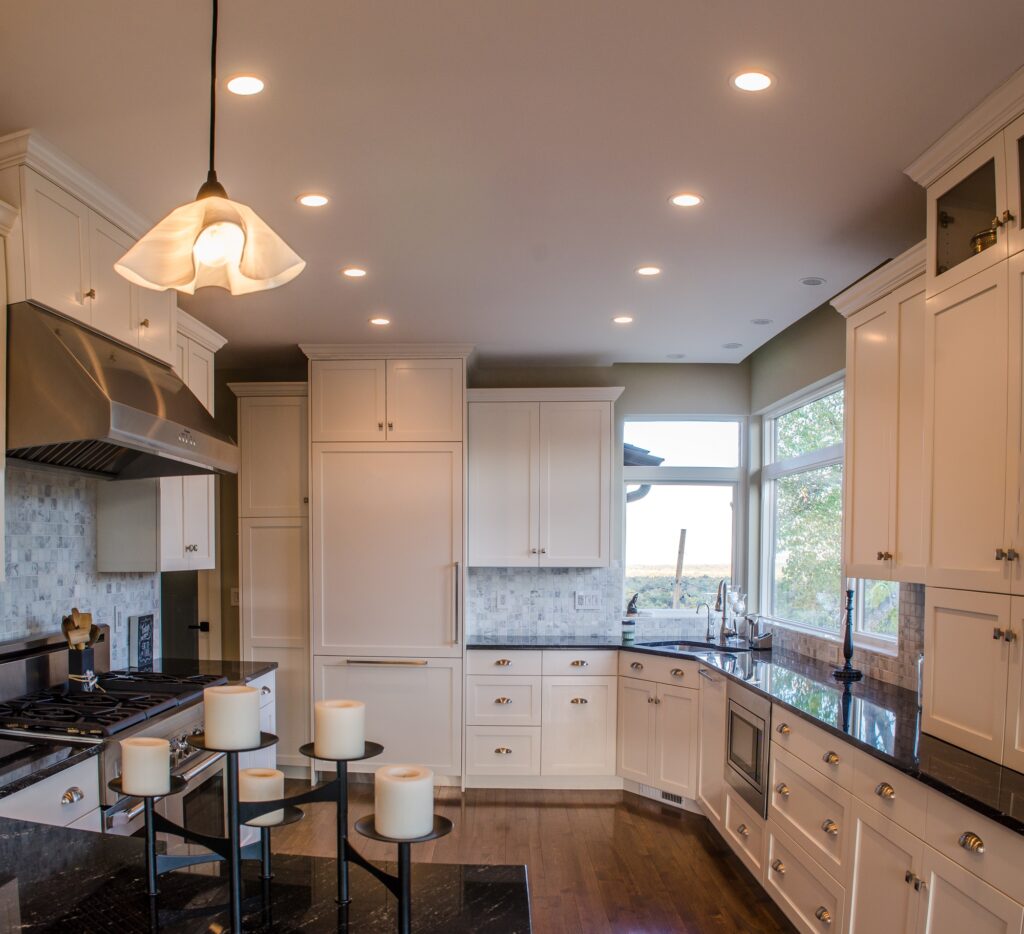 Modern kitchen with white custom cabinets, black countertops, stainless steel appliances, and recessed lighting