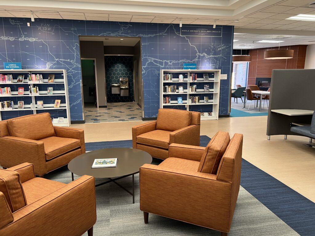Modern library lounge with comfortable chairs, bookshelves, map wall design, and collaborative reading space