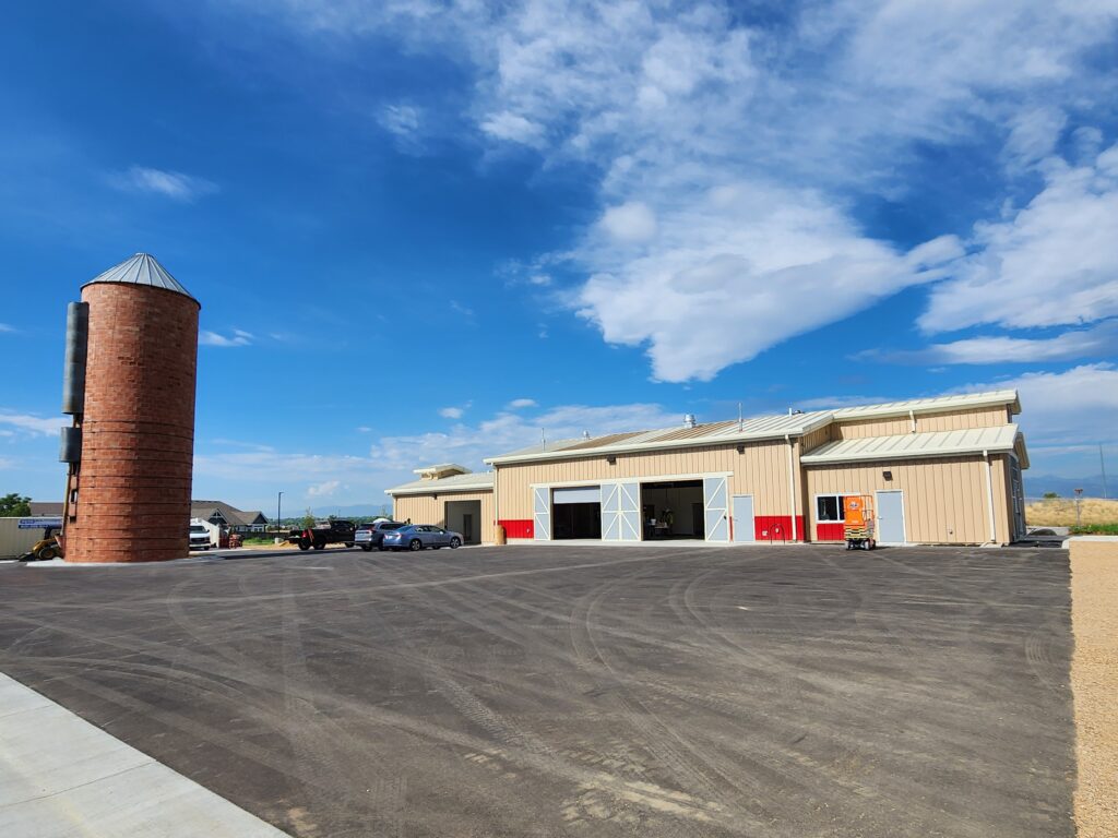 Exterior view of a modern agricultural facility with large storage spaces, silo structure, and functional site design by PEH Architects