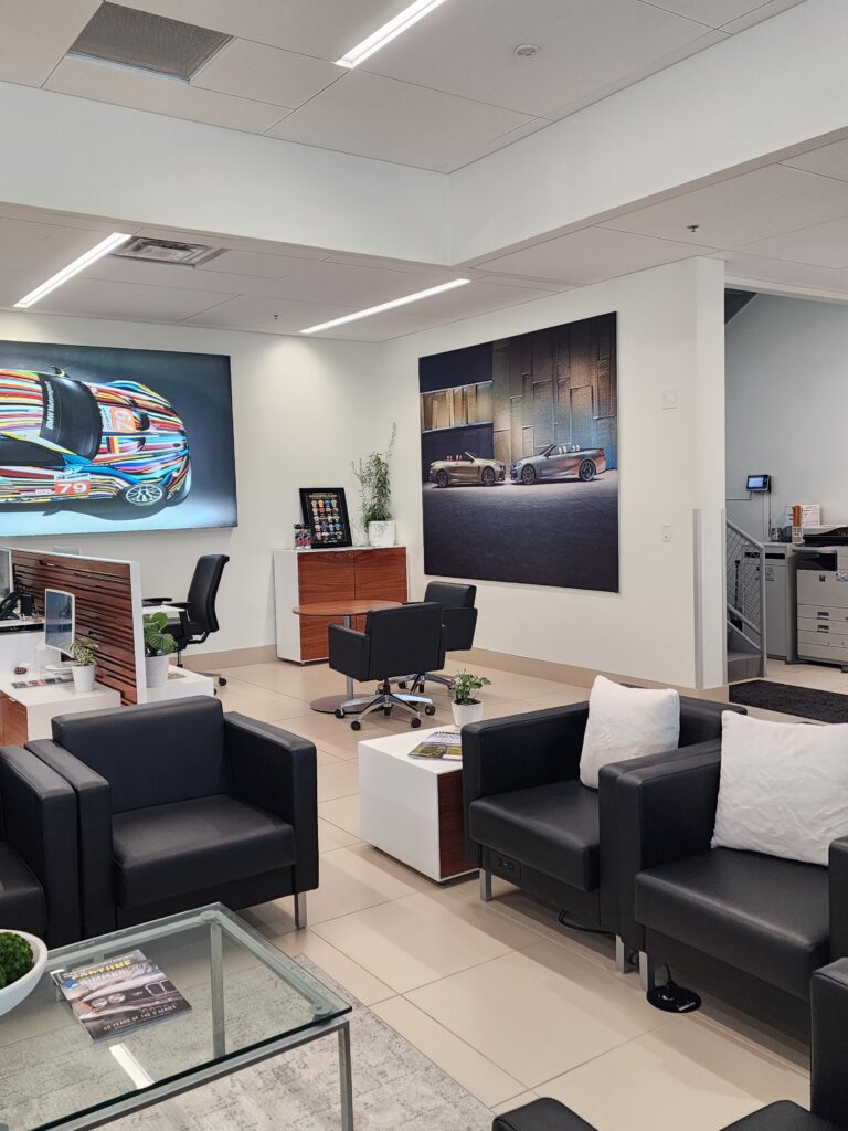 Modern BMW dealership customer lounge with comfortable seating, automotive artwork, and premium interior design elements