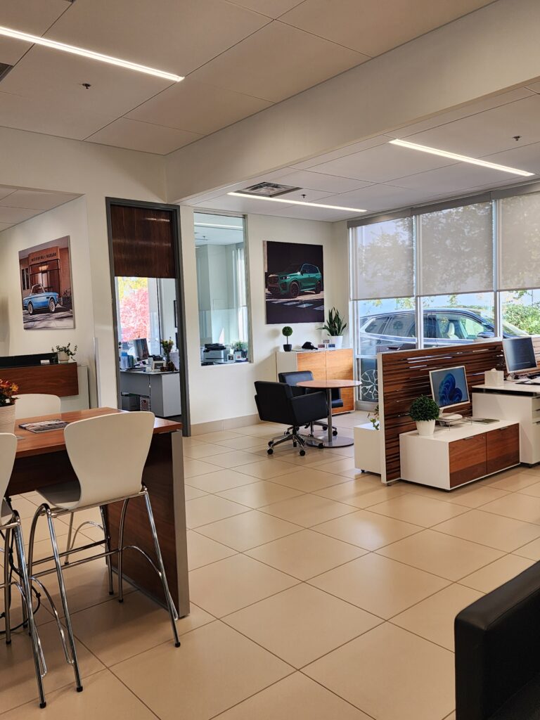 Modern BMW dealership office interior with customer consultation desks, glass partitions, and contemporary commercial design