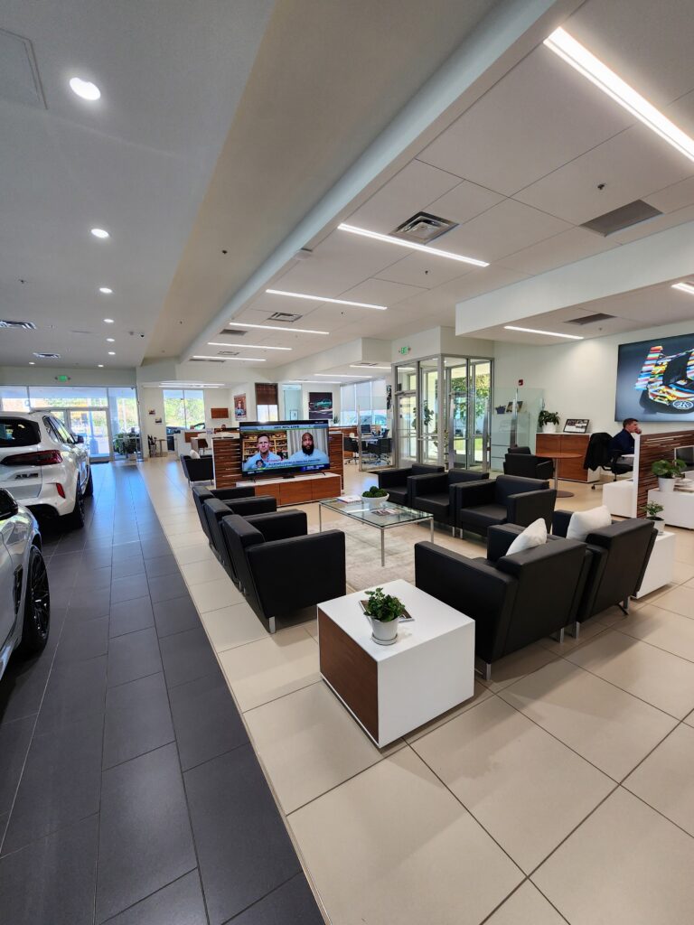Spacious BMW dealership showroom interior with customer lounge seating, display vehicles, and modern retail architecture