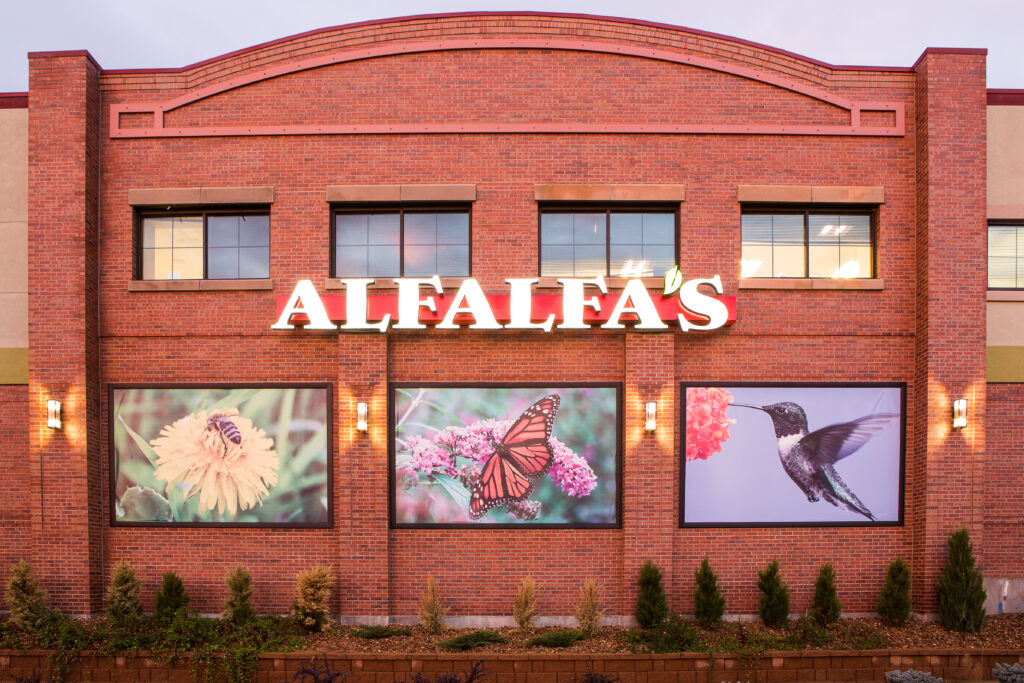 Commercial building with red brick facade, large windows, illuminated signage, and modern architectural exterior design
