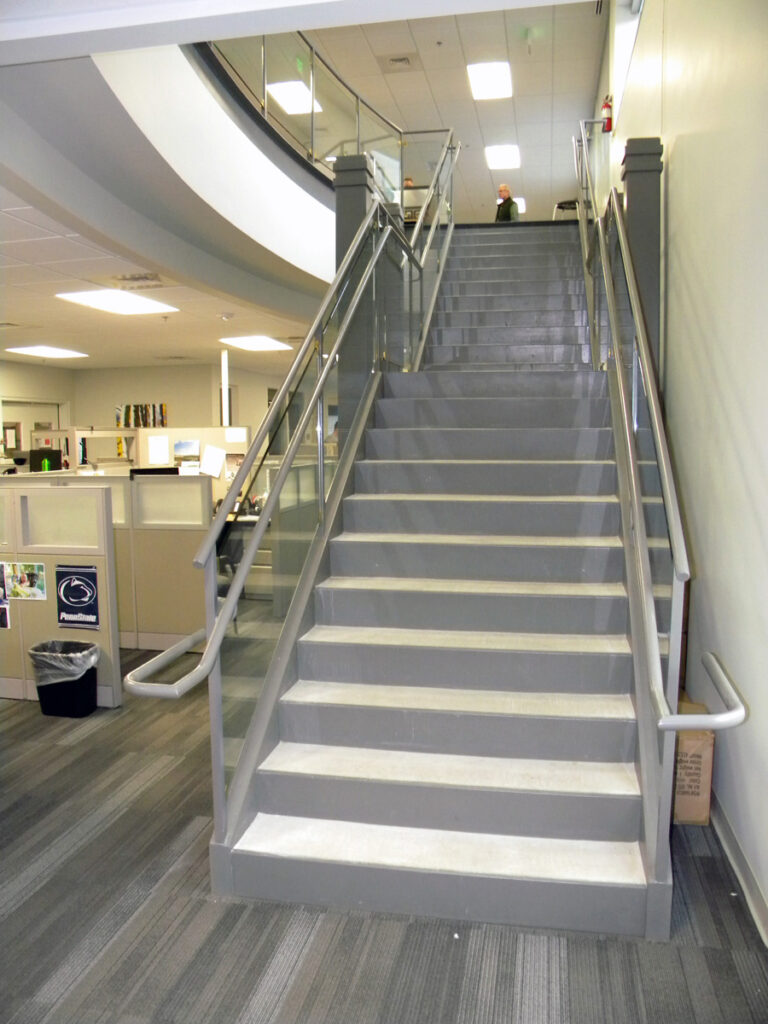 Modern commercial interior staircase with glass railings, office workspace, and contemporary architectural design by PEH Architects
