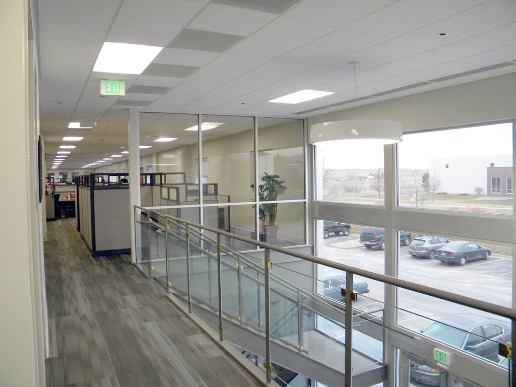 Modern commercial office interior with glass partitions, open workspace areas, staircase, and contemporary architectural design by PEH Architects