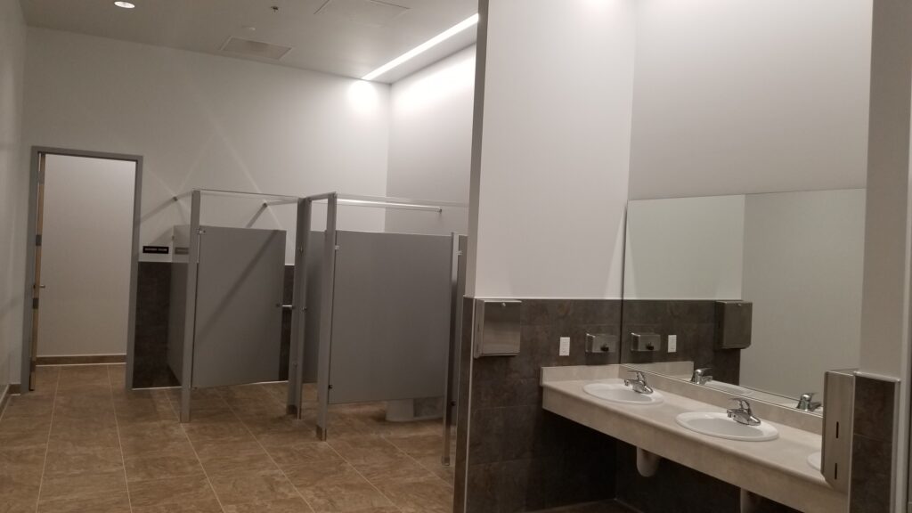 Modern commercial restroom interior with sinks, mirrors, privacy partitions, and functional architectural design by PEH Architects