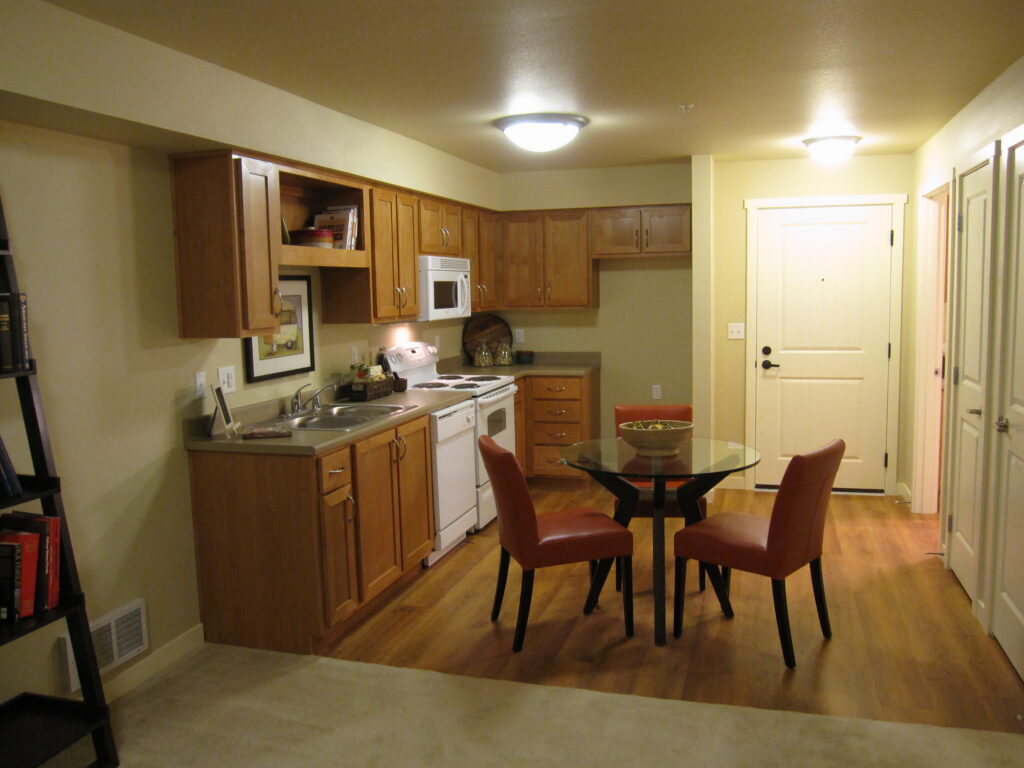 Modern kitchen interior with wooden cabinets, dining table, built-in appliances, and residential architectural design