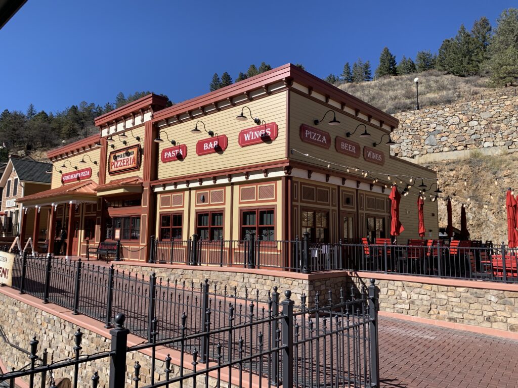 Copper Kitchen Pizzeria building with traditional exterior design, stone walls, outdoor seating, and commercial architecture