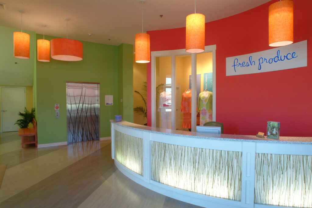 Modern office lobby with curved reception desk, colorful accent walls, pendant lighting, and contemporary interior architecture