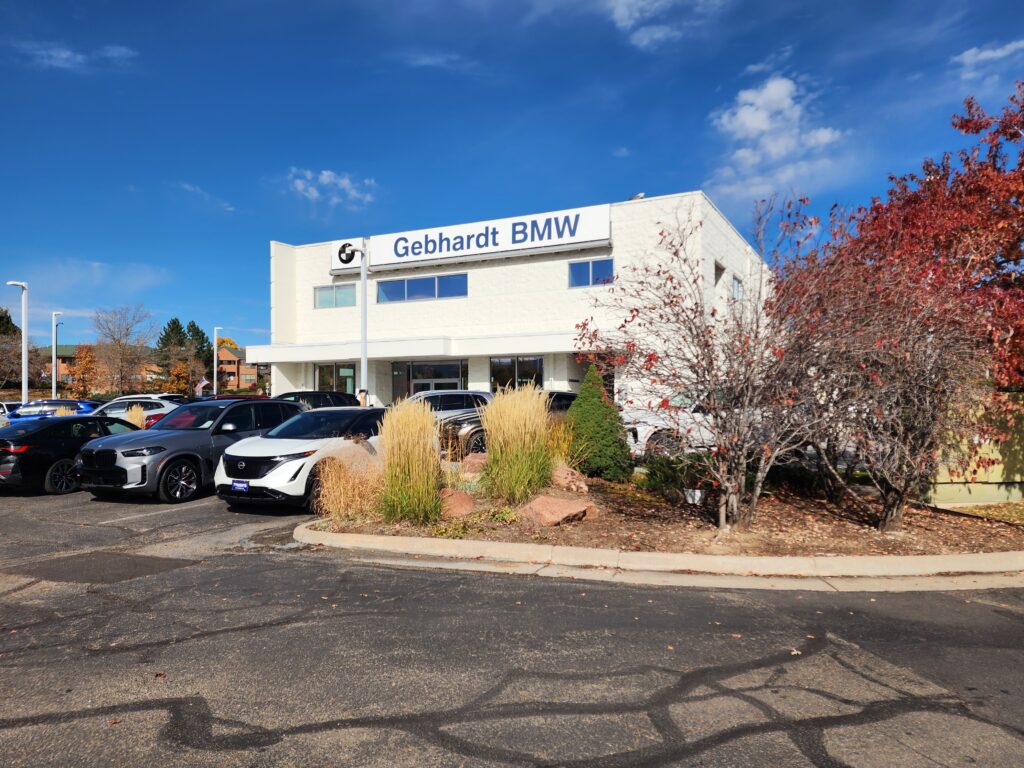 Gebhardt BMW dealership building exterior with modern white facade, parked vehicles, and landscaped entrance area