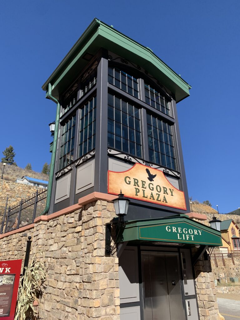 Modern Gregory Plaza elevator tower with stone facade, glass windows, and green architectural detailing