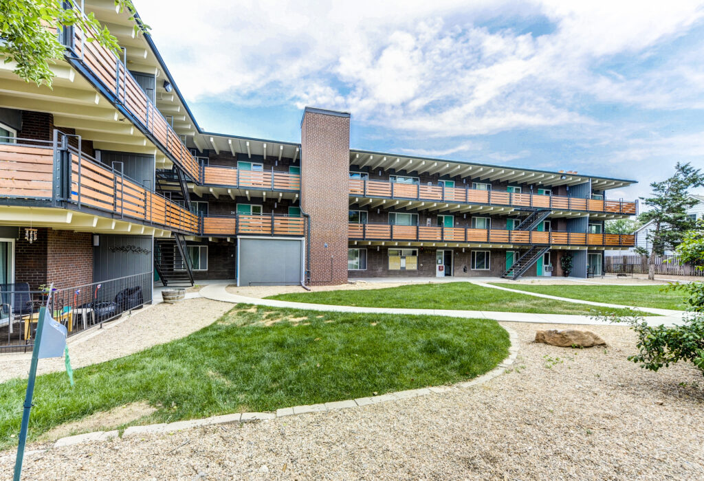 Modern apartment building exterior with balconies, landscaped lawn, and contemporary residential architecture