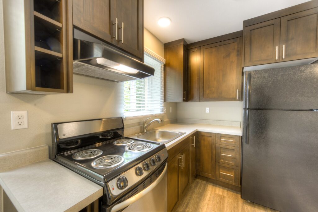 Modern apartment kitchen interior with wooden cabinets, stainless steel appliances, countertops, and functional layout design