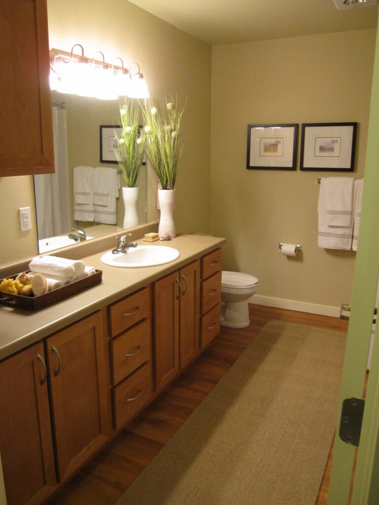 Modern bathroom interior with wooden vanity cabinets, mirror, sink, and contemporary lighting design