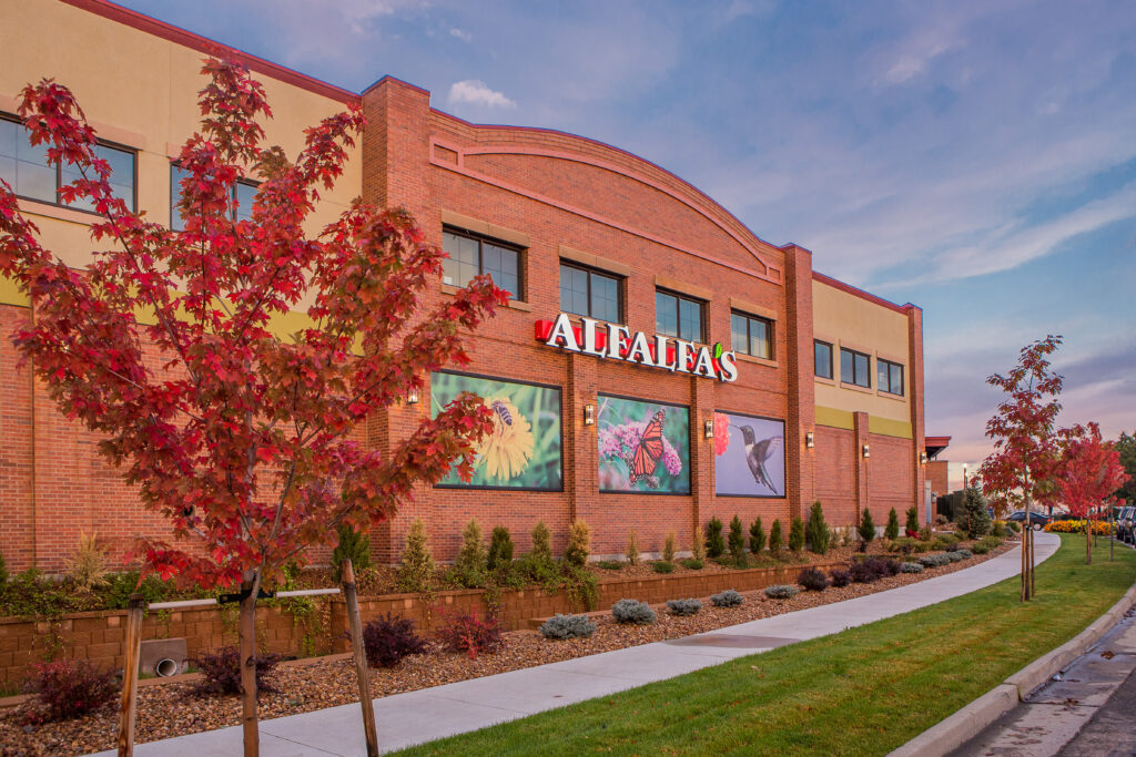Modern commercial building exterior with brick facade, landscaped entrance, large windows, and contemporary architectural design