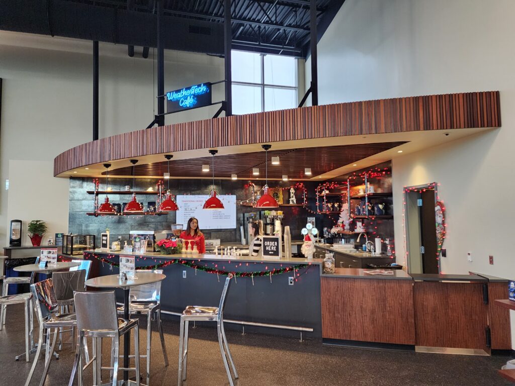 Modern cafe interior with coffee counter, seating area, pendant lighting, and contemporary architectural design