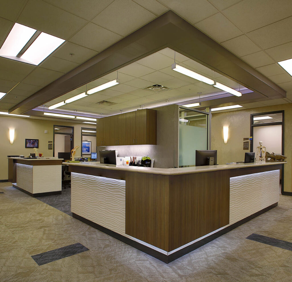 Modern healthcare reception desk interior with custom cabinetry, lighting design, and professional medical office layout