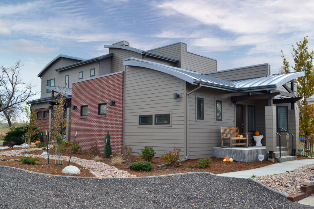 PEH Architects modern home exterior with brick facade, curved roof design, and landscaped yard