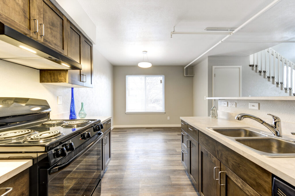 Modern kitchen interior with dark cabinets, countertop, stove, sink, and open living space design
