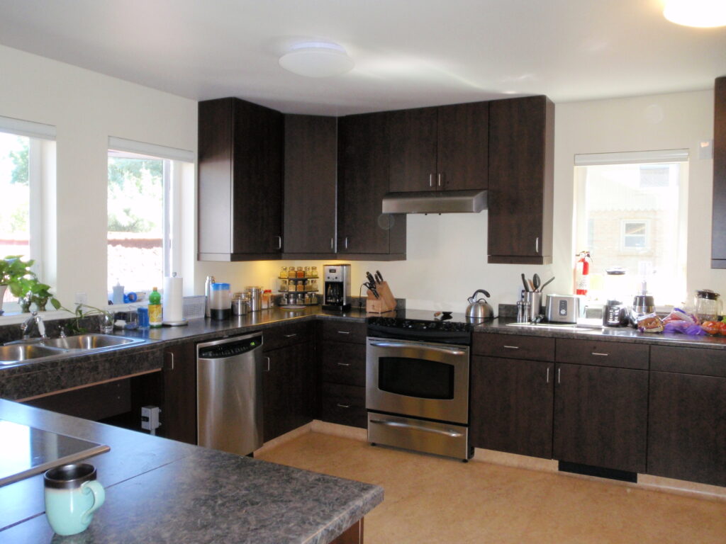 Modern kitchen interior design with dark cabinets, granite countertops, stainless steel appliances, and natural lighting