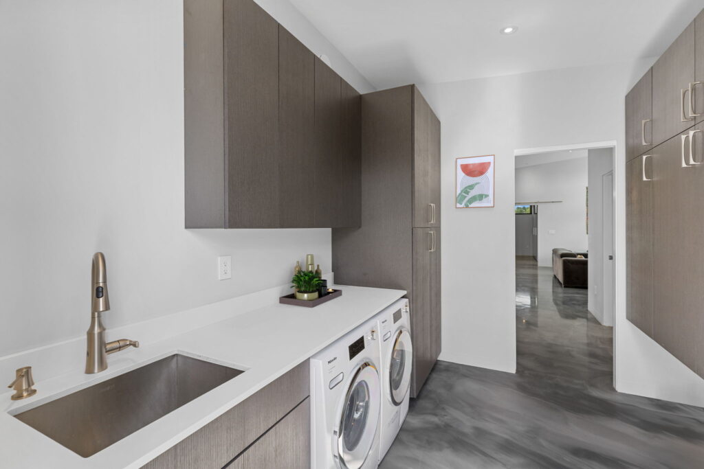 PEH Architects modern laundry room interior with custom cabinets and washer dryer area