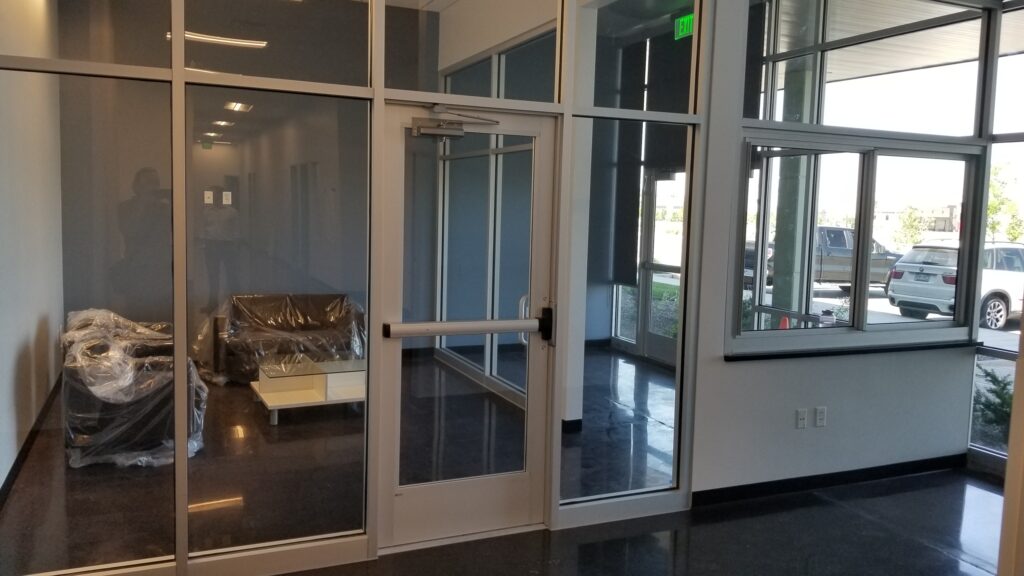Modern office entrance interior with glass partitions, natural lighting, polished flooring, and contemporary workplace design by PEH Architects