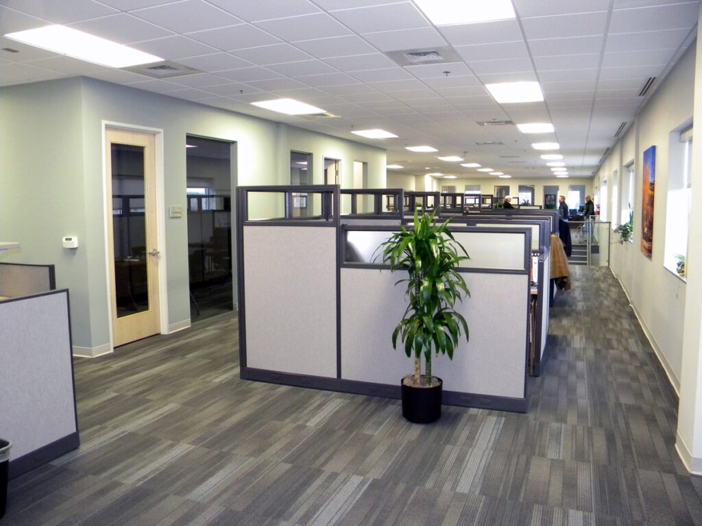 Modern office interior with open workstations, cubicles, natural lighting, and functional workspace design by PEH Architects