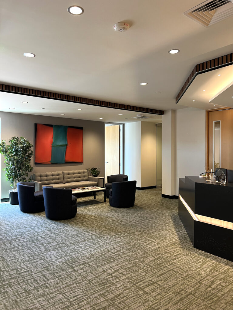 Modern office reception area with lounge seating, reception desk, artwork, and contemporary interior design