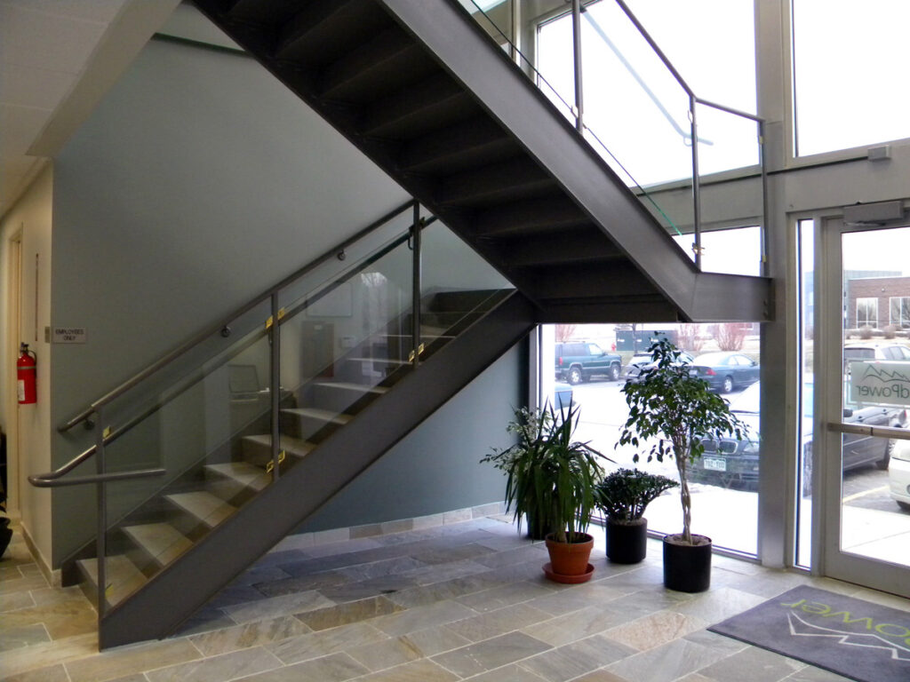 Modern office interior staircase with glass railings, natural lighting, and contemporary architectural design by PEH Architects
