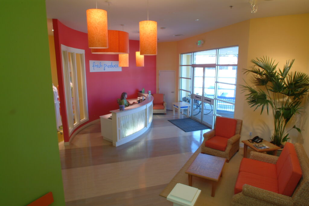 Modern office reception area with curved front desk, lounge seating, colorful walls, and contemporary interior design