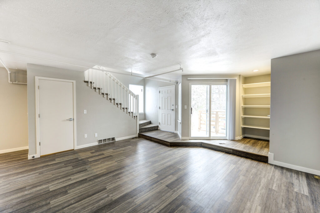 Modern open living room interior with staircase, wood flooring, built-in shelves, and contemporary home design