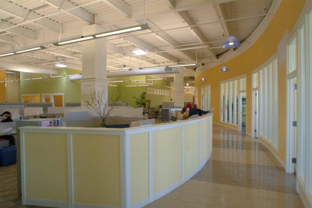 Open office workspace with curved reception area, cubicles, glass offices, and modern interior architecture