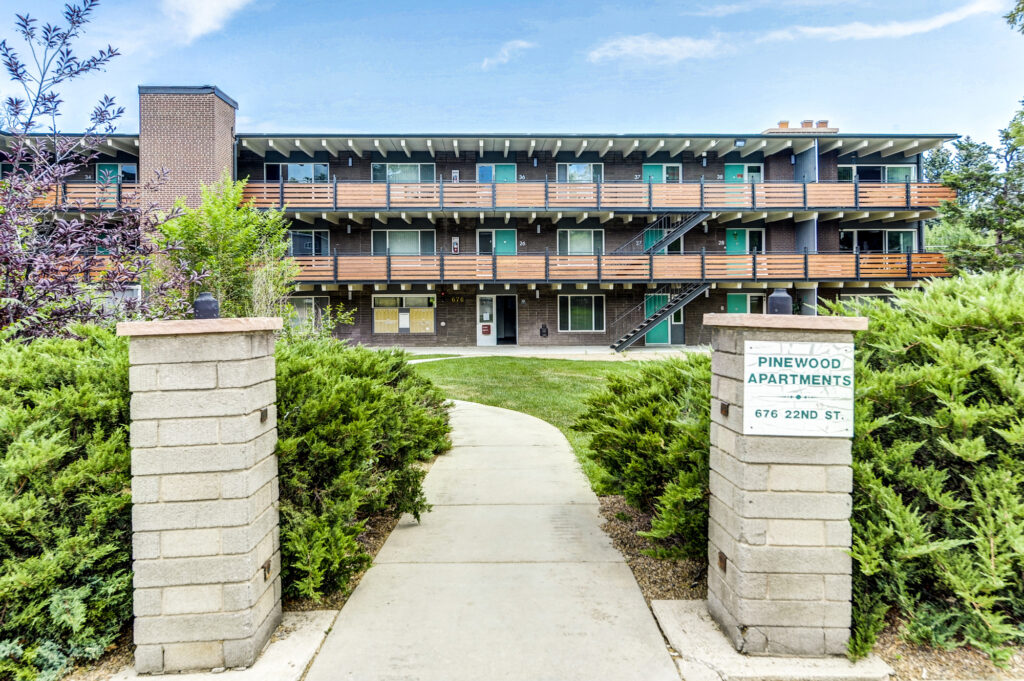 Pinewood apartment building exterior with balconies, landscaped entrance, and modern residential architecture