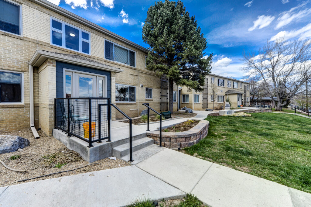 Modern residential building exterior with brick walls, landscaped lawn, walkways, and contemporary architectural design