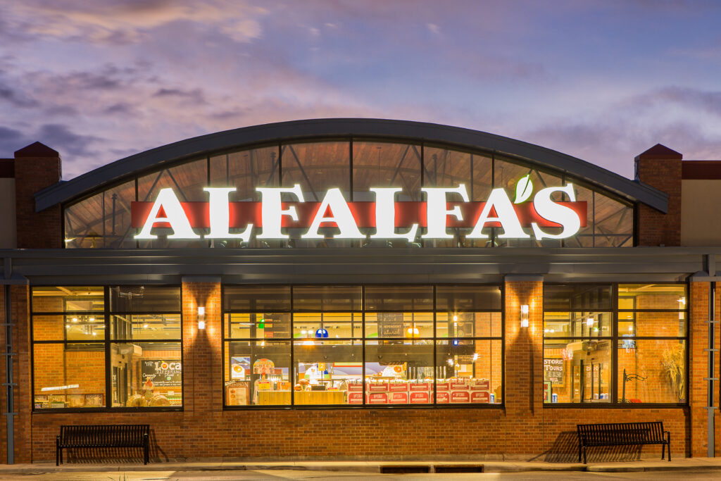 Modern retail building front elevation with illuminated signage, glass facade, brick exterior, and architectural lighting