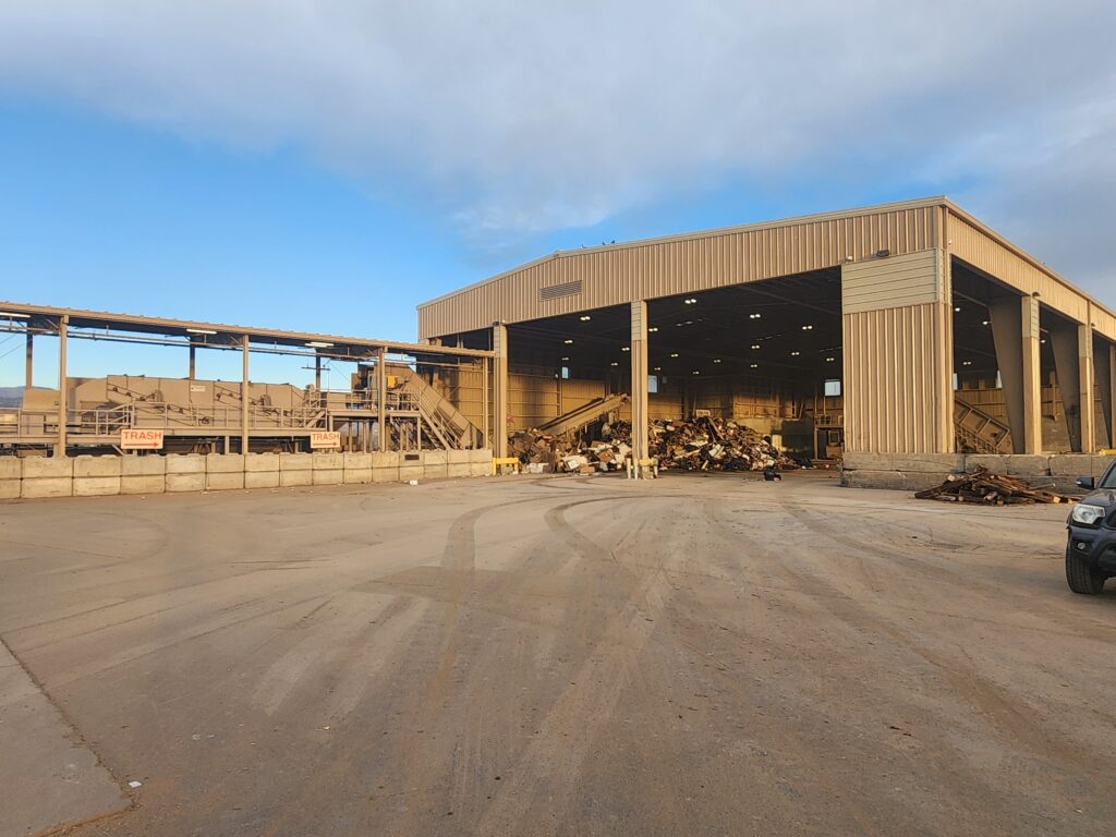 Industrial waste processing facility with large metal building structure, sorting equipment, and outdoor operational area