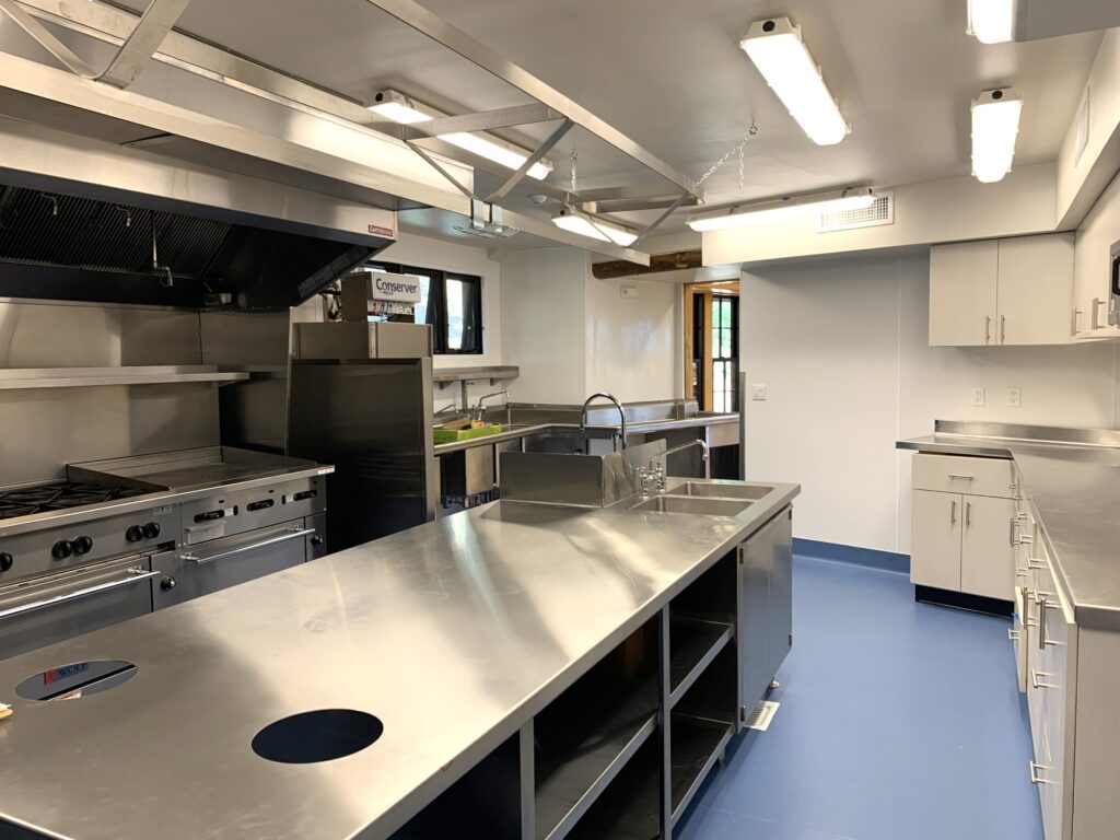 Modern commercial kitchen with stainless steel countertops, cooking equipment, sinks, and storage cabinets
