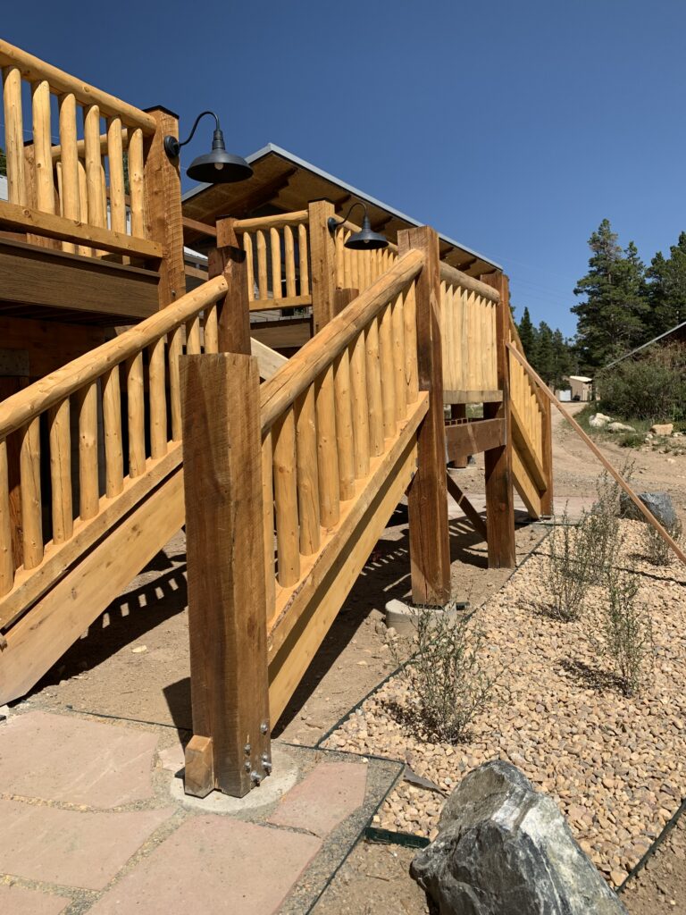 Custom wooden deck stairs with log railings and timber supports leading to an outdoor deck area