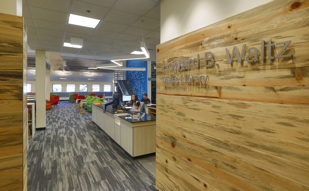 Interior entrance of Howard B. Waltz Music Library featuring wooden signage wall, reception desk, study area, and modern library design