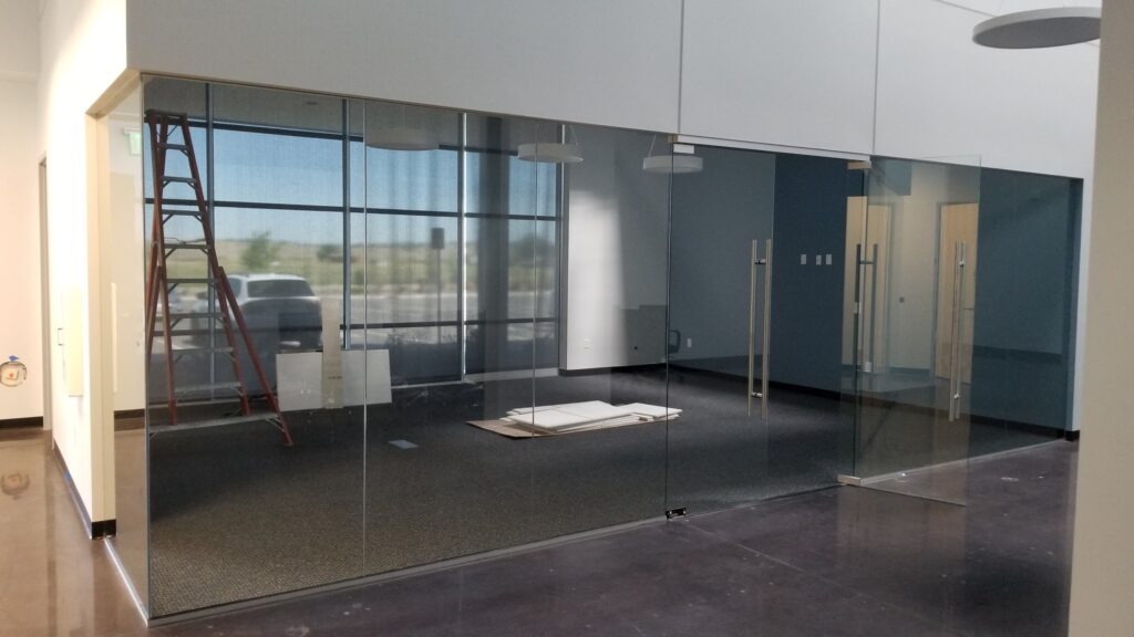 Modern office interior with glass meeting room walls, polished concrete floor, and unfinished commercial workspace installation