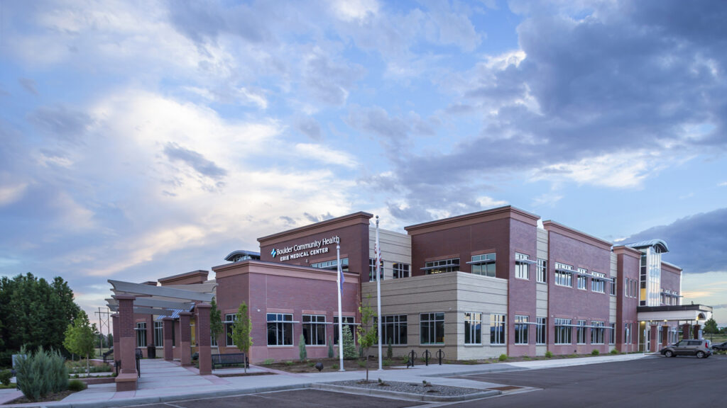 Modern healthcare medical center exterior with brick facade, glass windows, entrance walkway, and landscaped surroundings