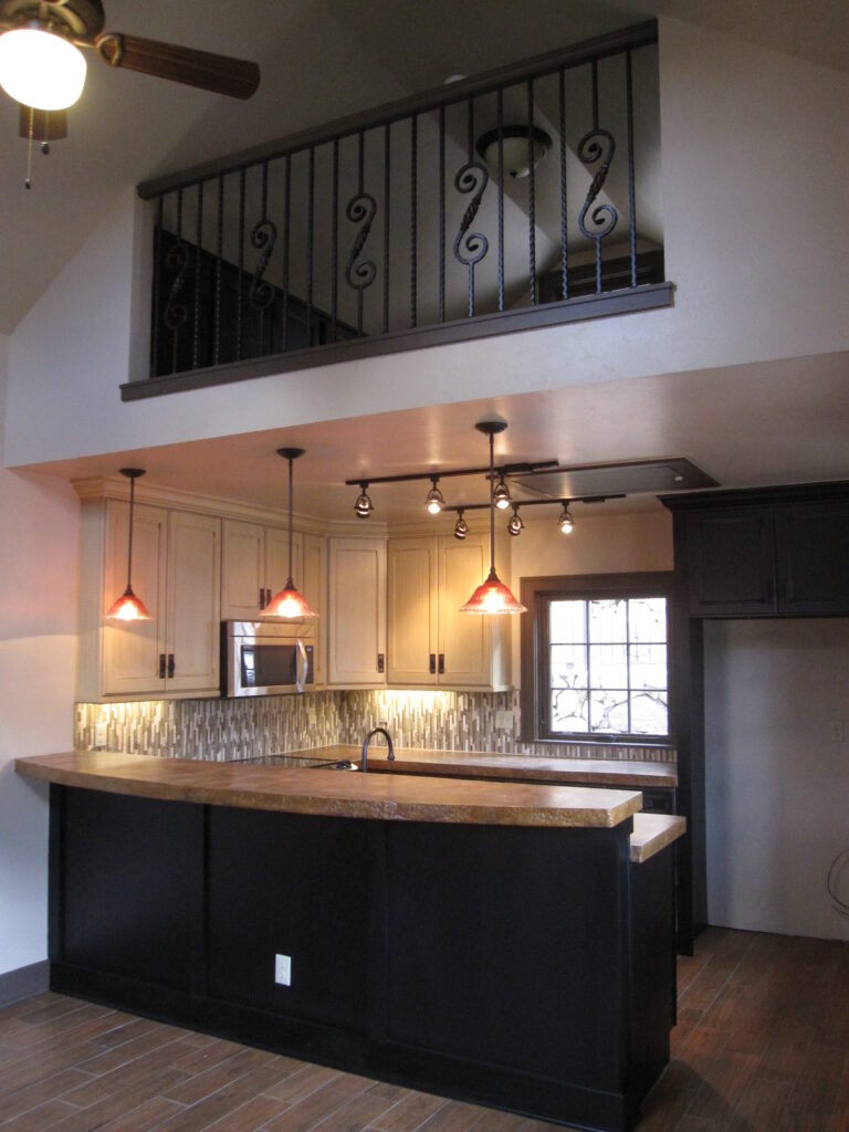 Modern kitchen renovation featuring black island, custom cabinets, backsplash, pendant lights, and open layout