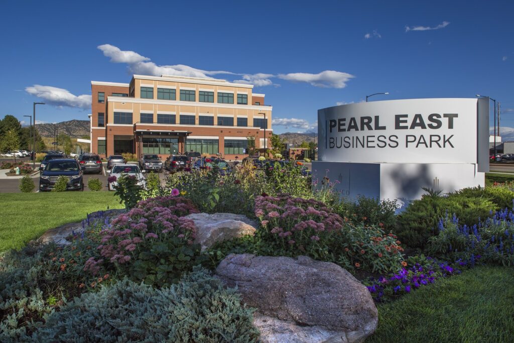Pearl East Business Park office building with landscaped entrance, corporate signage, parking area, and mountain background
