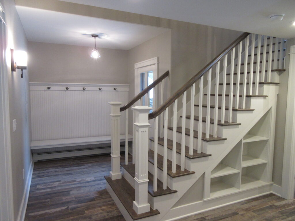 Chase Street Historic Home staircase renovation featuring restored wood handrails, custom built-in shelving, traditional wall details, and interior design by PEH Architects in Boulder
